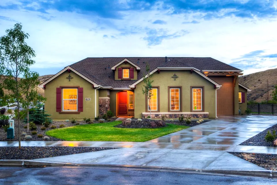 A well kept single story home with a wide driveway at dusk