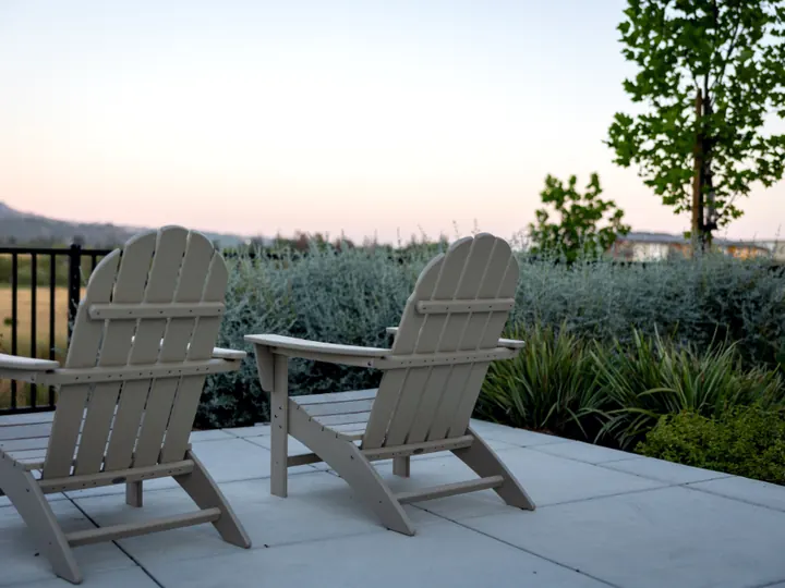A clean concrete patio with two wooden chairs